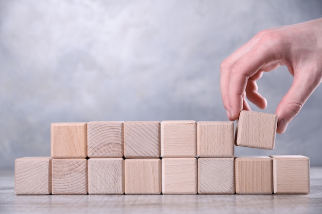 La mano pone el cubo de madera en blanco