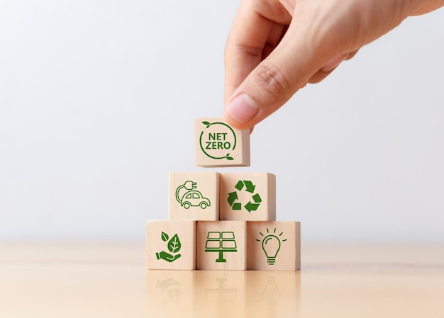 Foto la mano pone cubos de madera con el icono net zero en la mesa