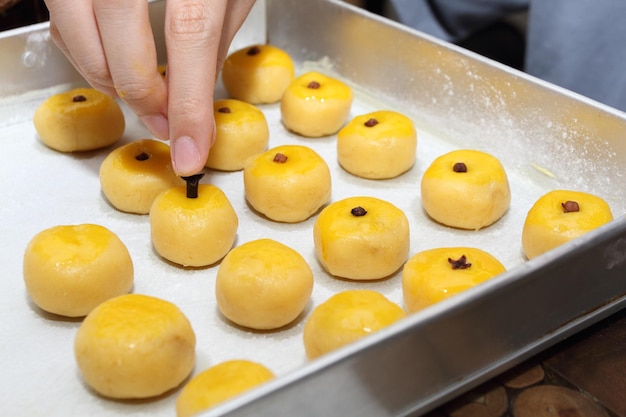 Una mano poner un diente a cada Nastar o Tarta de Piña en bandeja de aluminio antes de hornear