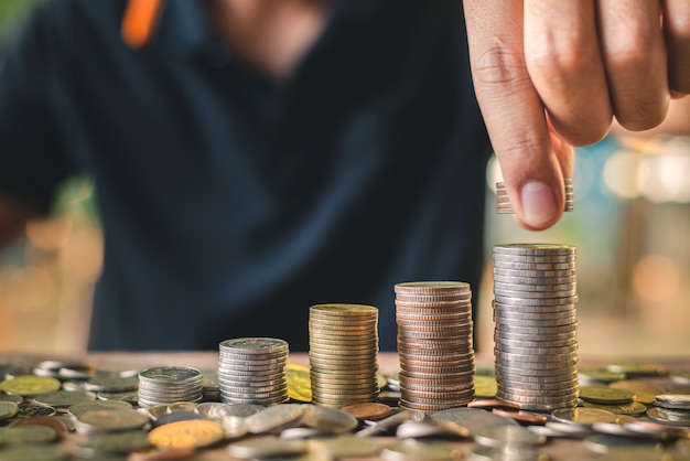 mano poniendo la moneda en la pila de monedas creciendo