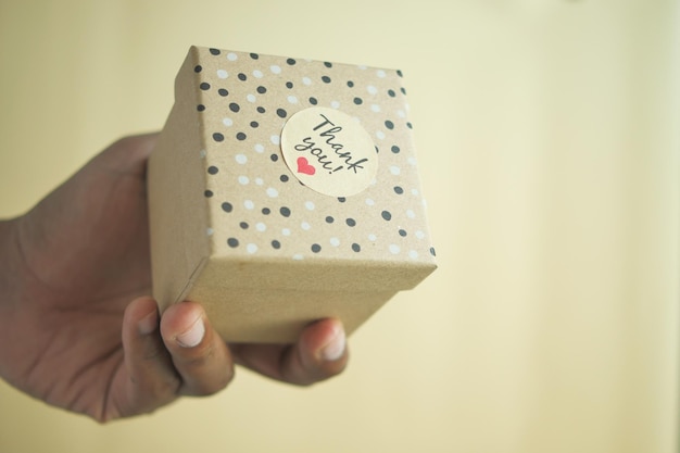 la mano poniendo una pegatina de agradecimiento en una caja de regalos