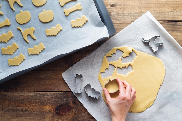 Mano preparando galletas en diferentes formas para Halloween. Copie el espacio.