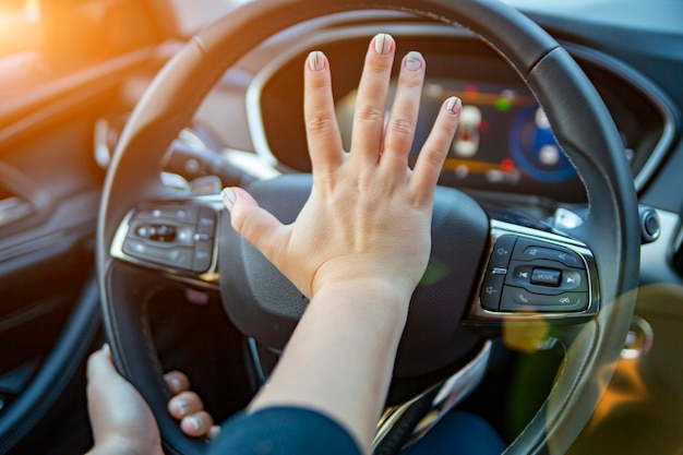 Mano presiona la bocina en el volante de un automóvil moderno sin rostro