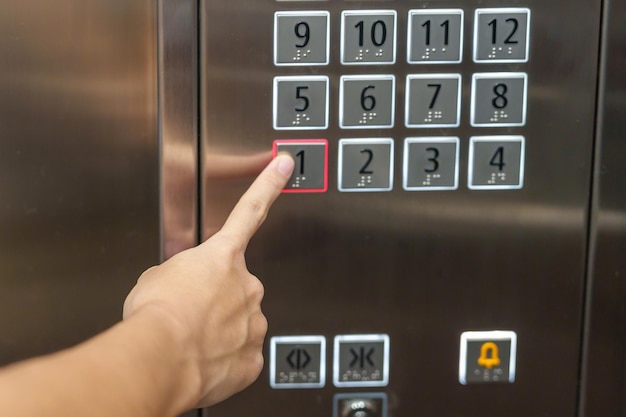 La mano presiona con el dedo el botón del ascensor mujer que usa el ascensor en la oficina o apartamento
