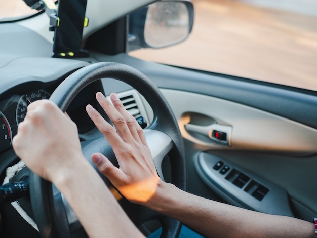 Foto mano del primer conductor presionando la bocina de un auto mientras se conduce