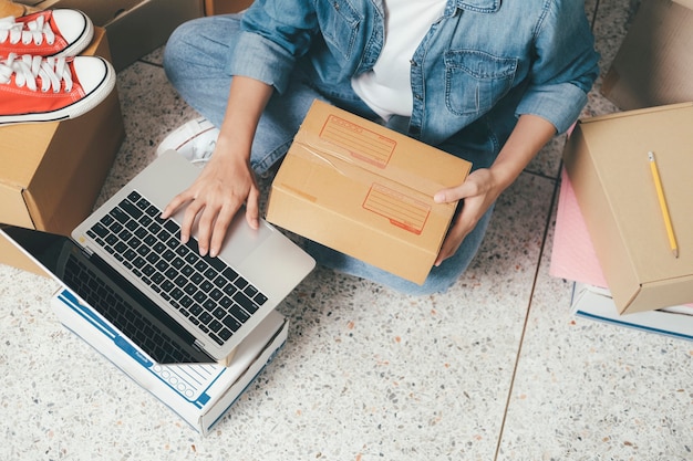 Mano del primer de la dirección de la escritura de la mujer joven en la caja del paquete para la orden de entrega al cliente, envío y logística, comerciante en línea y vendedor, dueño del negocio o pyme, compras en línea.