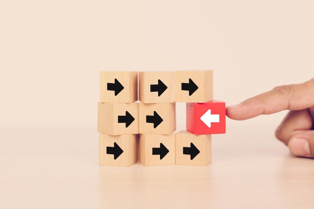 La mano del primer elige el icono de la flecha en el bloque de juguete de madera del cubo apilado