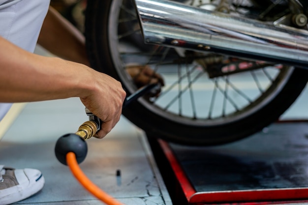 Mano del primer hombre que controla los neumáticos de aire con un manómetro en el servicio de reparación de automóviles