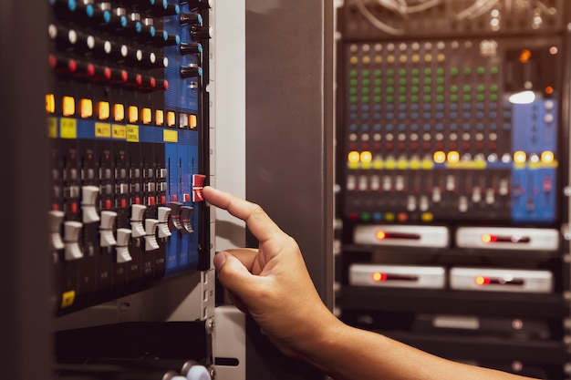 Foto mano de primer plano ajusta el volumen del mezclador de sonido en el lugar de trabajo del estudio.