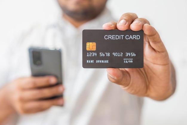 Mano de primer plano de un hombre asiático con camisa blanca que sostiene una tarjeta de crédito negra en la mano aislada sobre fondo blanco Concepto de negocio de tecnología social de comunicación financiera comercial