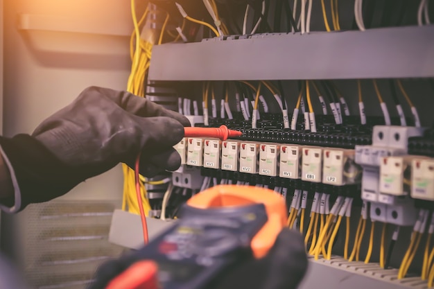 Mano de primer plano de la ingeniería eléctrica mediante medición para comprobar la electricidad.