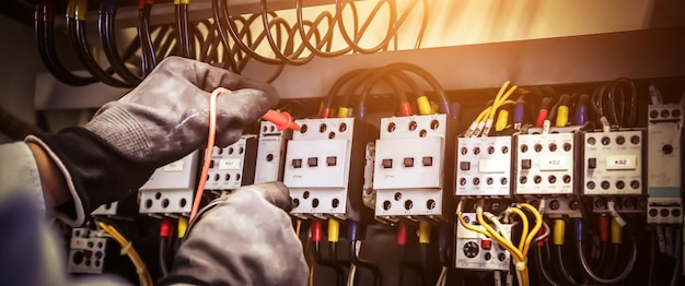 Mano de primer plano de la ingeniería eléctrica utilizando la medición para comprobar la electricidad.