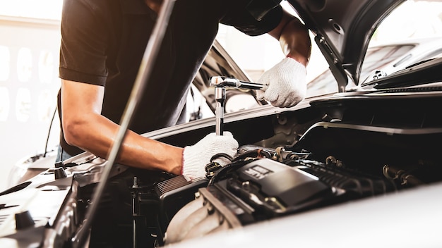 Mano de primer plano de mecánico de automóviles con llave para reparar el motor de un automóvil.