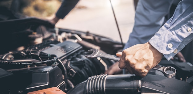 Mano de primer plano de mecánico de automóviles con llave para reparar el motor de un automóvil.