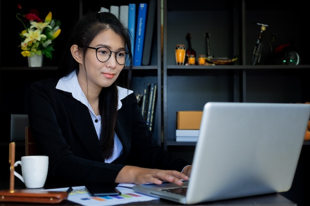 Mano de primer plano de mujeres de negocios con papel escrito en gráfico, usando computadora portátil y teléfono inteligente, negocio de marketing para el concepto de éxito.