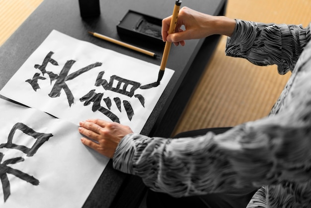 Foto mano de primer plano pintar letras japonesas