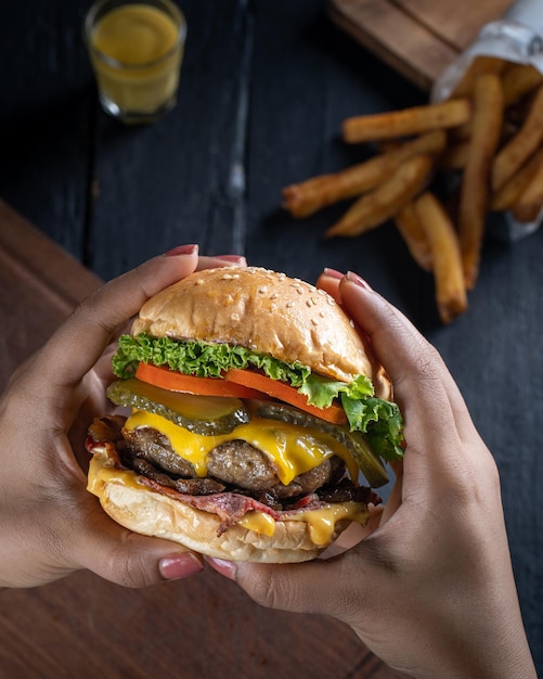 Mano de primer plano que sostiene la vista superior de la sabrosa hamburguesa