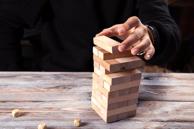 La mano del primer toma un bloque en una torre de bloques de madera