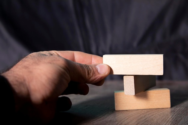 La mano del primer toma un bloque en una torre de bloques de madera