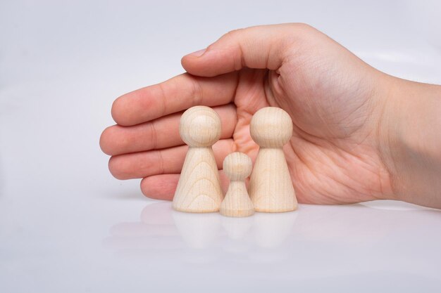 Mano protegiendo figuras de madera de personas como concepto familiar