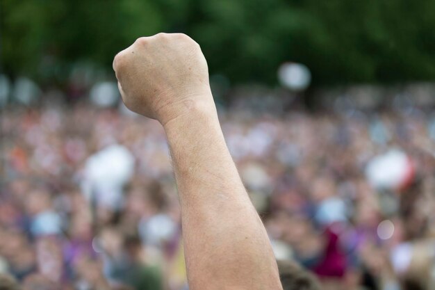 Una mano en un puño en protesta contra una multitud de gente borrosa