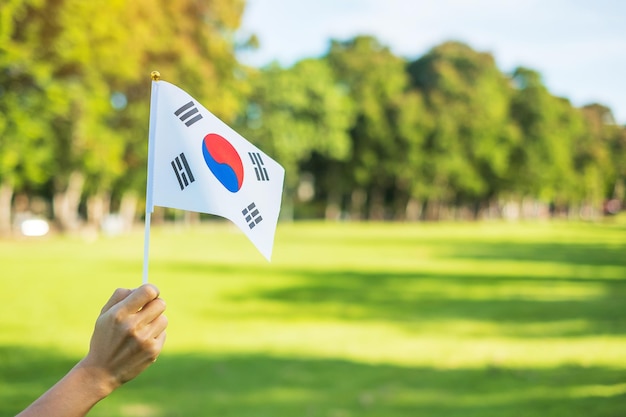 Mano que sostiene la bandera de Corea en el fondo de la naturaleza Fundación Nacional Gaecheonjeol fiesta pública de la Nación Día de la Liberación Nacional de Corea y conceptos de celebración feliz