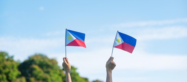 Mano que sostiene la bandera de Filipinas en el fondo de la naturaleza 12 de junio del Día de la Independencia y conceptos de celebración feliz