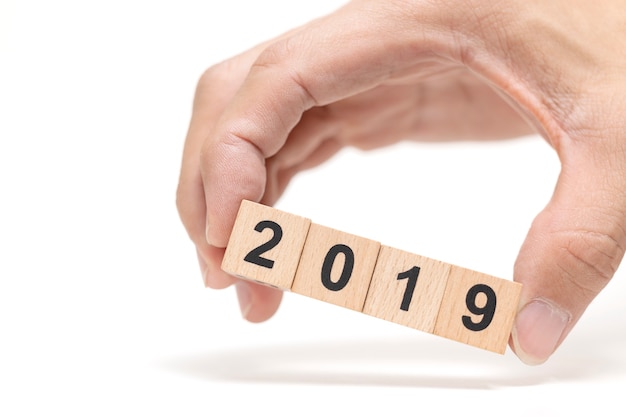 Mano que sostiene el bloque de madera 2019 sobre fondo blanco, concepto de feliz año nuevo