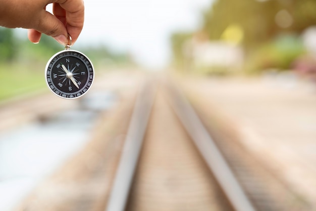 Mano que sostiene la brújula en el fondo del ferrocarril