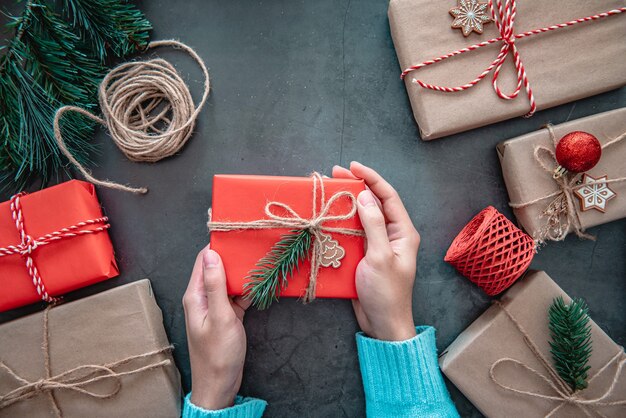 Mano que sostiene la caja de regalo de Navidad sobre superficie negra