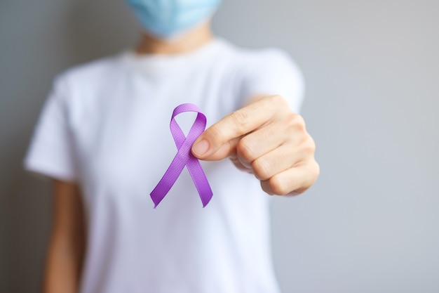 Foto mano que sostiene la cinta púrpura para el mes de concienciación sobre el cáncer de páncreas, esófago, testículo, alzheimer mundial, epilepsia, lupus, sarcoidosis, fibromialgia y violencia doméstica. concepto del día mundial del cáncer