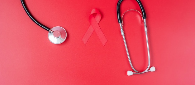 Mano que sostiene la cinta roja para apoyar el mes de concientización sobre el cáncer