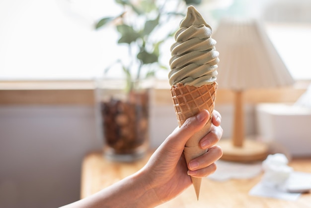 Mano que sostiene el cono de helado Helado de té verde