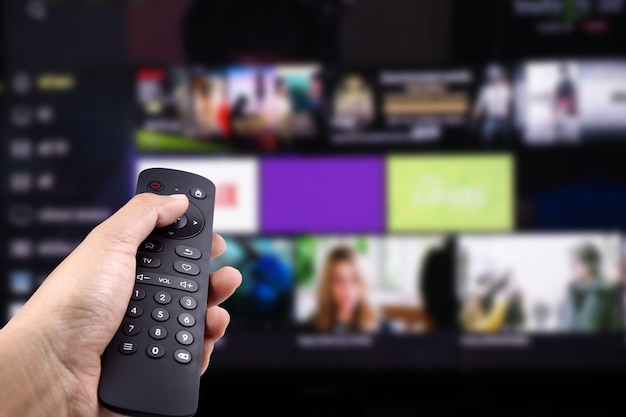 Foto mano que sostiene el control remoto de tv con smart tv