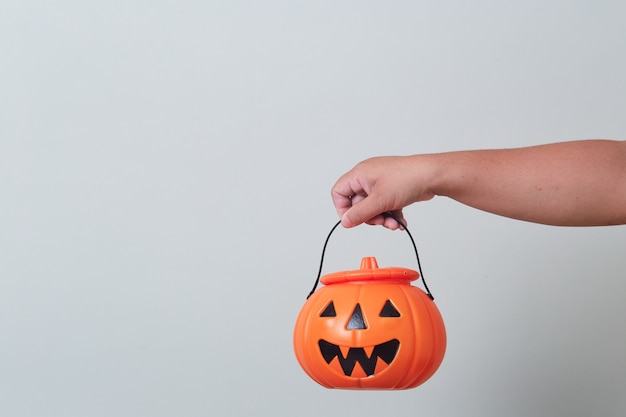 Mano que sostiene el cubo de calabaza de halloween