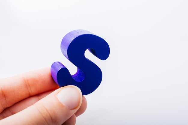 Mano que sostiene el cubo de letras S del alfabeto