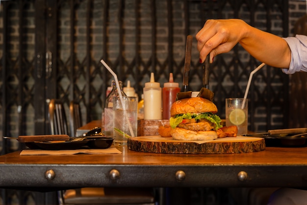 Mano que sostiene el cuchillo con hamburguesa con agua de soda.