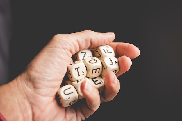 Mano que sostiene los dados de letras en la oscuridad