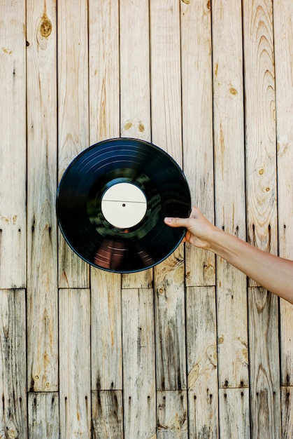 Mano que sostiene el disco de vinilo sobre fondo de madera