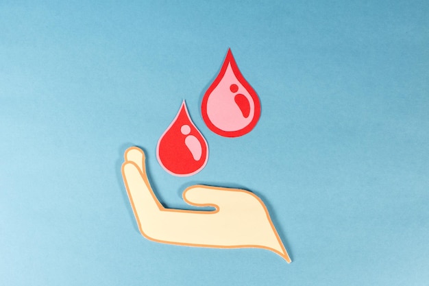 Una mano que sostiene dos gotas rojas de sangre concepto de donación de sangre