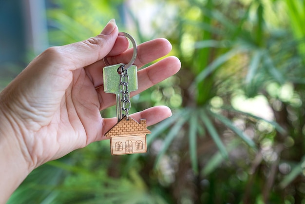 Mano que sostiene la llave de la casa con el fondo de la naturaleza de la palmera