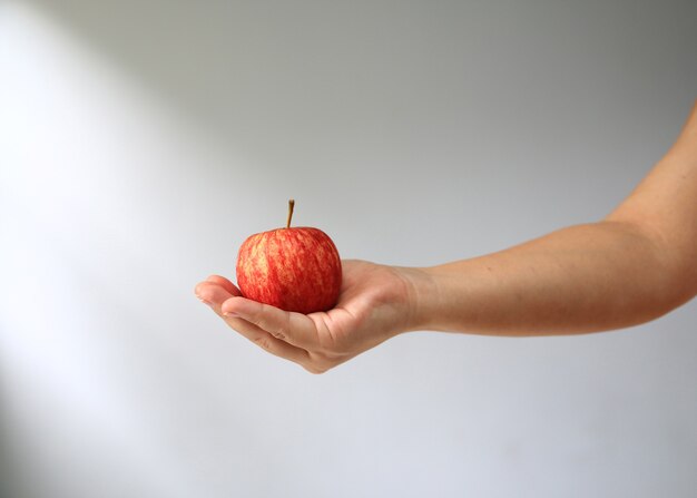 Mano que sostiene la manzana roja.