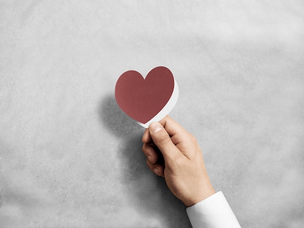 Mano que sostiene la maqueta de la tarjeta de San Valentín roja en blanco