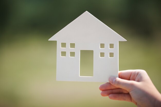 Mano que sostiene el modelo de casa al aire libre