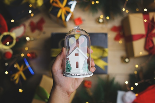 Mano que sostiene el ornamento de cristal de la Navidad sobre la decoración de la Navidad. Vista superior