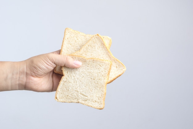 Mano que sostiene el pan de grano entero en rodajas