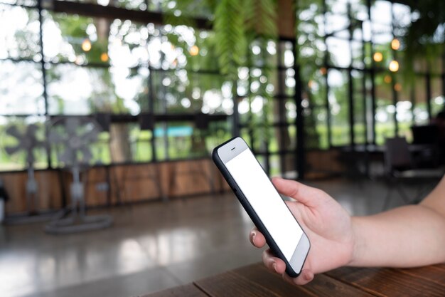 Mano que sostiene la pantalla vacía del teléfono móvil en la cafetería de la cafetería