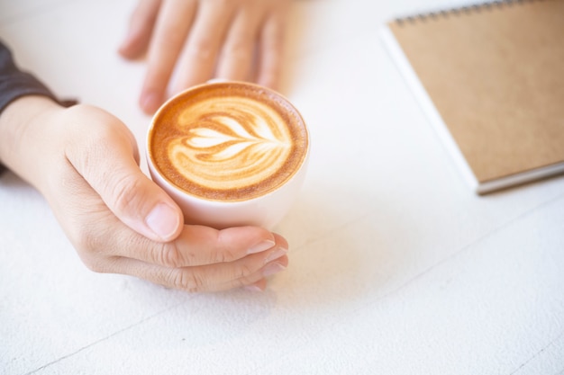 Mano que sostiene la taza de café en la mesa