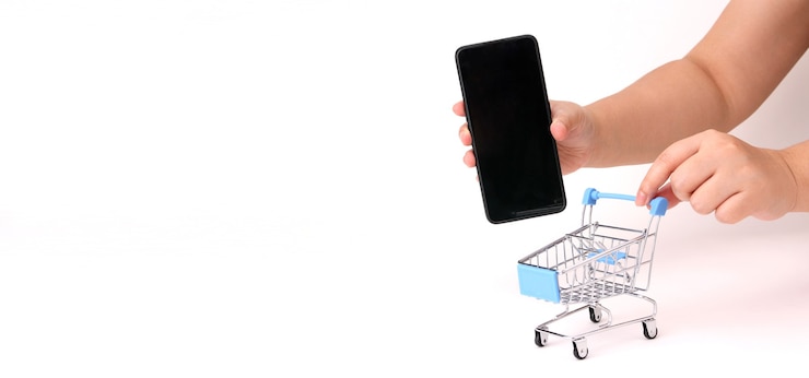 Foto una mano que sostiene el teléfono inteligente y empuja el carrito de la compra.