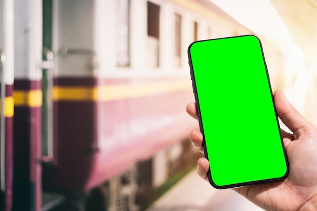 Mano que sostiene el teléfono inteligente en la estación de tren